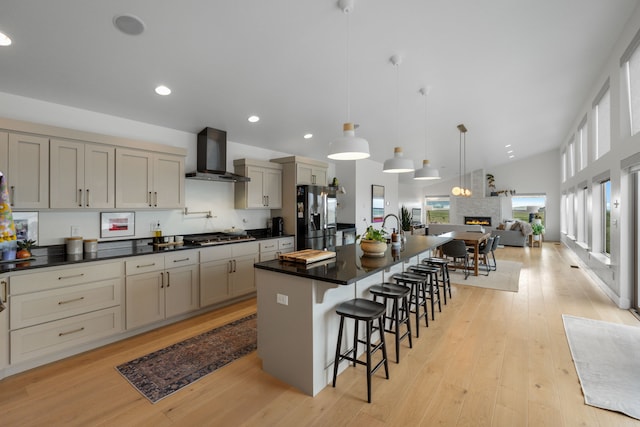 4910 Lauryn Ct, Helena, MT 59602 - kitchen with wall chimney exhaust hood, stainless steel appliances, dark countertops, a breakfast bar, and open floor plan