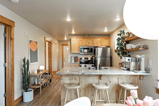 1245 Waverly St Unit 301, Missoula, MT 59802 - kitchen with appliances with stainless steel finishes, a peninsula, a sink, light wood-style flooring, and a breakfast bar area