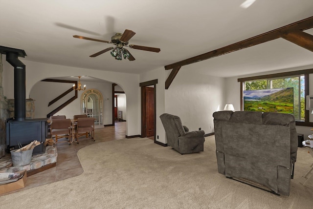 209 Caps Rd, Kalispell, MT 59901 - tiled living room with arched walkways, a wood stove, a chandelier, a ceiling fan, and carpet flooring