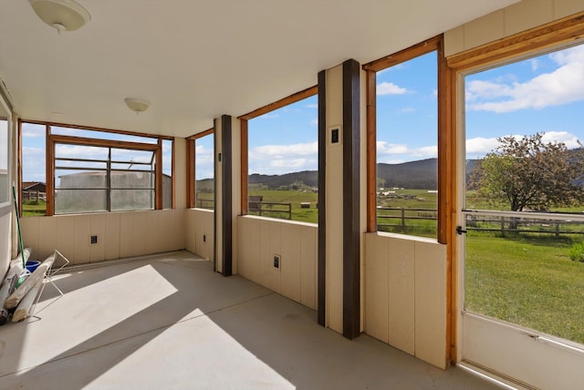209 Caps Rd, Kalispell, MT 59901 - unfurnished sunroom with finished concrete floors, a mountain view, and a view of countryside