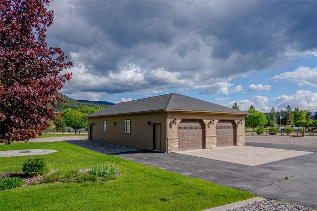 700 Airfield Rd, Libby, MT 59923 - view of home's exterior featuring stone siding, a lawn, a garage, a mountain view, and a shingled roof