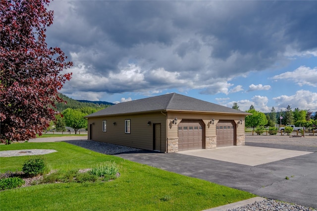 700 Airfield Rd, Libby, MT 59923 - view of side of property featuring a lawn, stone siding, a mountain view, roof with shingles, and a garage