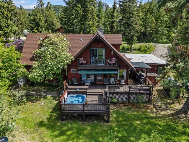 33893 Redgate Dr, Bigfork, MT 59911 - back of property featuring a wooden deck, a lawn, a wooded view, and a chimney