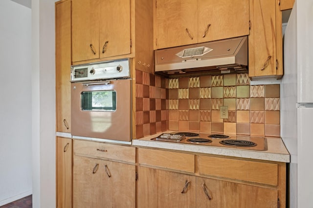 2015 Tower St, Missoula, MT 59804 - kitchen with wall oven, electric stovetop, under cabinet range hood, light countertops, and decorative backsplash