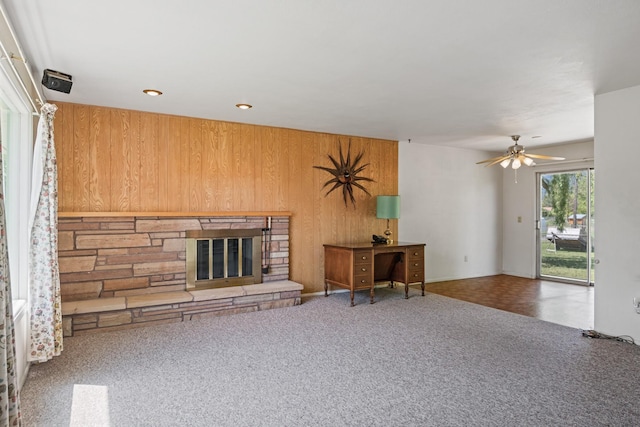 2015 Tower St, Missoula, MT 59804 - carpeted living area with wood walls, a stone fireplace, a ceiling fan, and recessed lighting