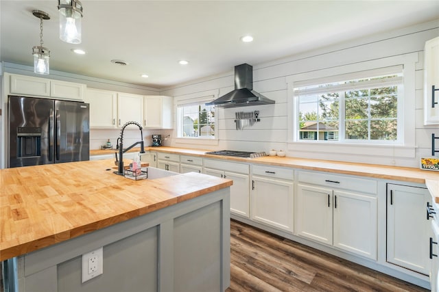 1296 Bighorn Rd, Helena, MT 59602 - kitchen featuring butcher block counters, stainless steel fridge with ice dispenser, wall chimney exhaust hood, a sink, and dark wood-style flooring