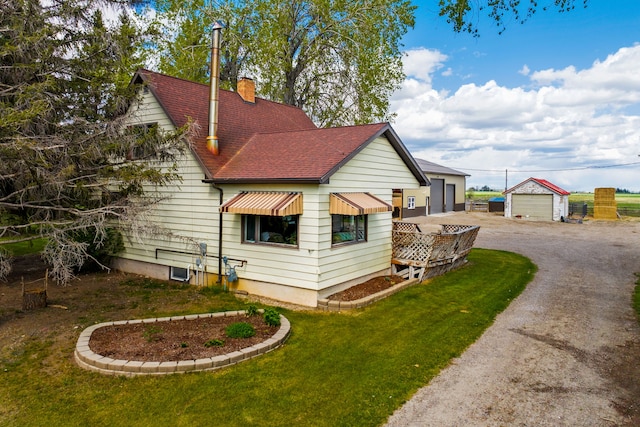 151 6th Ln NE, Fairfield, MT 59436 - view of side of property with a shingled roof, a chimney, dirt driveway, a yard, and an outbuilding