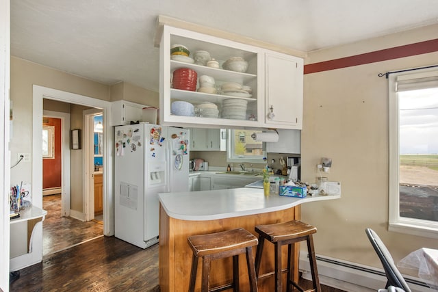 151 6th Ln NE, Fairfield, MT 59436 - kitchen featuring white refrigerator with ice dispenser, baseboard heating, dark wood-style floors, a peninsula, and light countertops