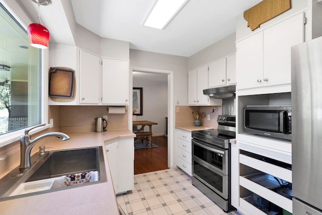 630 Woodworth Ave, Missoula, MT 59801 - kitchen with stainless steel appliances, light floors, under cabinet range hood, and white cabinetry