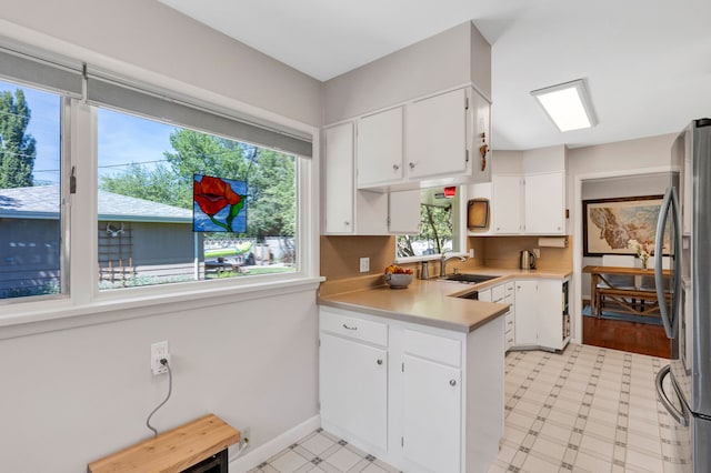 630 Woodworth Ave, Missoula, MT 59801 - kitchen featuring freestanding refrigerator, light countertops, white cabinets, a peninsula, and light floors