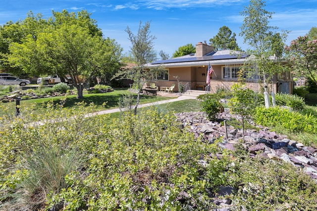 630 Woodworth Ave, Missoula, MT 59801 - ranch-style home featuring a chimney, roof mounted solar panels, and stucco siding