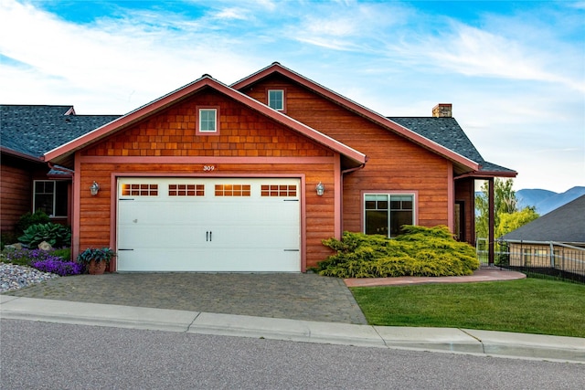 309 Timberwolf Dr, Polson, MT 59860 - view of front facade featuring a chimney, a shingled roof, a garage, and driveway