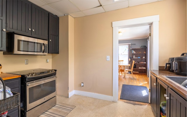 831 Hastings Ave, Missoula, MT 59801 - kitchen featuring stainless steel appliances, baseboards, a paneled ceiling, dark countertops, and dark cabinets