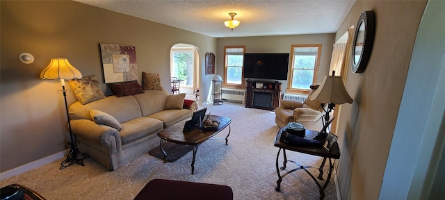 225 4th Ave SE, Dutton, MT 59433 - carpeted living room with radiator heating unit, a textured ceiling, arched walkways, and a fireplace