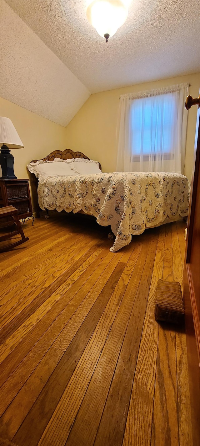 225 4th Ave SE, Dutton, MT 59433 - bedroom featuring hardwood / wood-style floors, lofted ceiling, and a textured ceiling