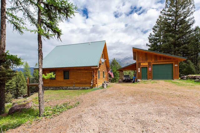 589 Summit Dr, Seeley Lake, MT 59868 - view of home's exterior featuring dirt driveway, log exterior, a detached garage, a metal roof, and a mountain view
