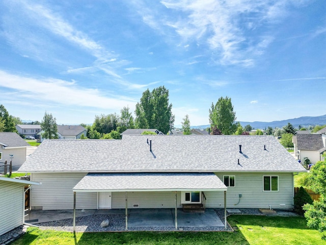 144 Beargrass Ln, Kalispell, MT 59901 - back of house with a patio, a shingled roof, a lawn, and a mountain view