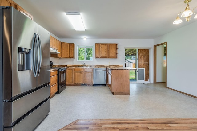 144 Beargrass Ln, Kalispell, MT 59901 - kitchen with appliances with stainless steel finishes, under cabinet range hood, brown cabinets, light flooring, and a sink