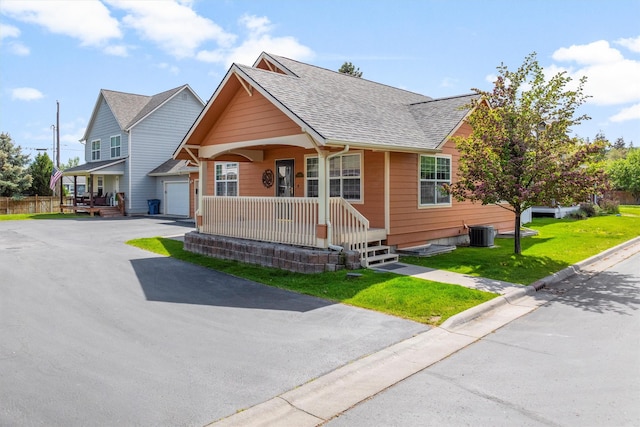 1337A Lily Ct, Missoula, MT 59802 - view of front of home featuring a porch, cooling unit, roof with shingles, a garage, and a front lawn