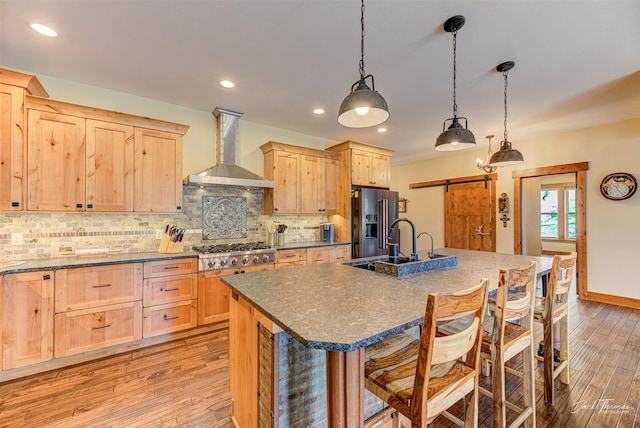 20 Penny Ln, Clancy, MT 59634 - kitchen with wall chimney range hood, stainless steel appliances, light brown cabinets, a barn door, and light wood-type flooring