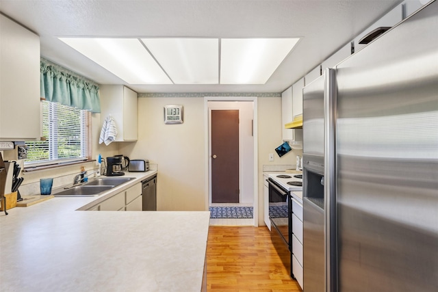 2404 56th St, Missoula, MT 59803 - kitchen with stainless steel appliances, under cabinet range hood, light countertops, a sink, and light wood finished floors