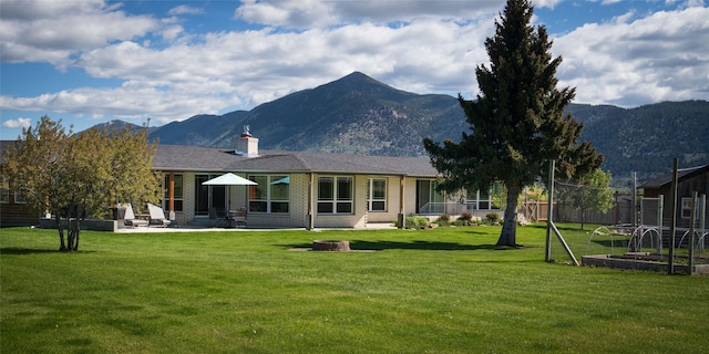345 Ash Dr, Butte, MT 59701 - rear view of house with a patio area, a mountain view, a chimney, and brick siding