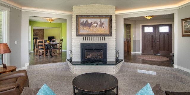 345 Ash Dr, Butte, MT 59701 - living room with a brick fireplace, carpet flooring, baseboards, ornamental molding, and wood finished floors