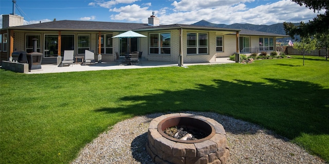 345 Ash Dr, Butte, MT 59701 - back of property with a chimney, a fire pit, brick siding, and a patio