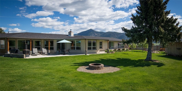 345 Ash Dr, Butte, MT 59701 - back of house with a fire pit, a patio area, a mountain view, a chimney, and brick siding
