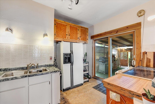 1712 1st Ave N, Great Falls, MT 59401 - kitchen featuring white fridge with ice dispenser, a sink, dark stone countertops, brown cabinetry, and decorative backsplash