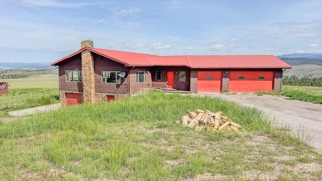 6180 Elkhorn Rd, Helena, MT 59602 - view of front facade with a chimney, dirt driveway, a garage, metal roof, and a mountain view