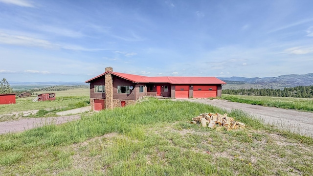 6180 Elkhorn Rd, Helena, MT 59602 - view of front facade featuring dirt driveway, a chimney, an attached garage, a mountain view, and metal roof