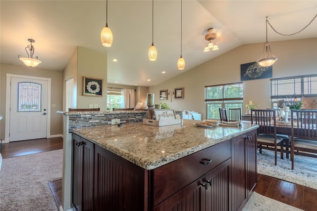 5946 Johnson Rd, East Helena, MT 59635 - kitchen featuring vaulted ceiling, light stone countertops, dark wood-style flooring, dark brown cabinetry, and decorative light fixtures