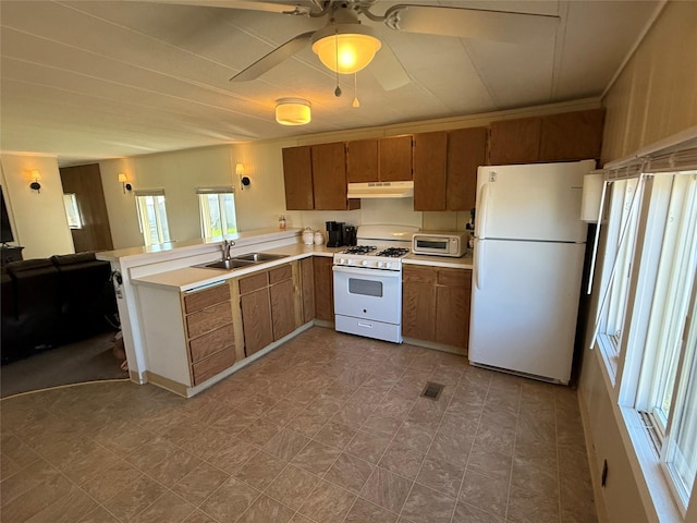 991 Phillips Rd, Helena, MT 59602 - kitchen with white appliances, under cabinet range hood, a sink, brown cabinetry, and light countertops