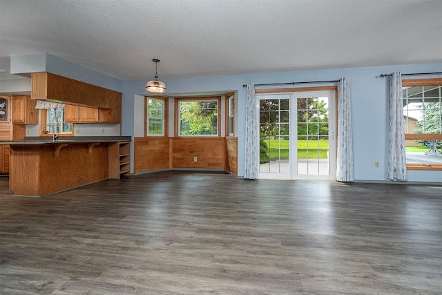 33958 Connolly Way, Polson, MT 59860 - kitchen featuring dark countertops, open floor plan, dark wood-style floors, brown cabinets, and a kitchen bar