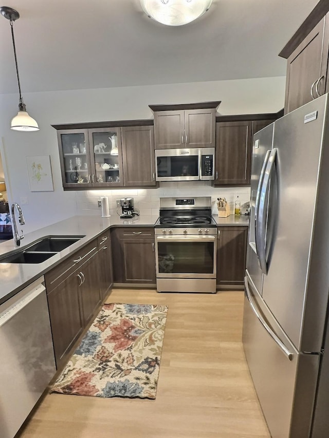 100 Woodlands Way Unit W-204, Kalispell, MT 59901 - kitchen featuring stainless steel appliances, dark brown cabinetry, light wood finished floors, glass insert cabinets, and decorative light fixtures