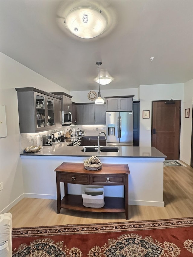 100 Woodlands Way Unit W-204, Kalispell, MT 59901 - kitchen featuring stainless steel appliances, light wood-style floors, glass insert cabinets, a peninsula, and decorative light fixtures