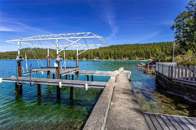 29137 Rocky Point Rd, Polson, MT 59860 - dock featuring boat lift, a wooded view, and a water view