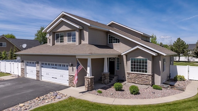 25 Logan Way, Kalispell, MT 59901 - view of front of home with stone siding, a porch, asphalt driveway, and roof with shingles