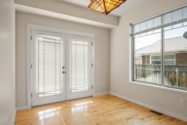 2211 S Russell St Unit B, Missoula, MT 59801 - unfurnished room featuring healthy amount of natural light, french doors, light wood-style flooring, and baseboards