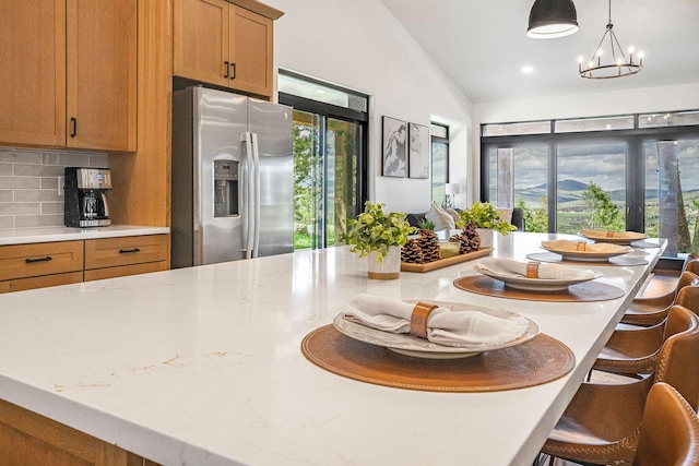 77 Rumsey Rd, Philipsburg, MT 59858 - kitchen featuring stainless steel refrigerator with ice dispenser, decorative backsplash, a kitchen bar, brown cabinets, and lofted ceiling