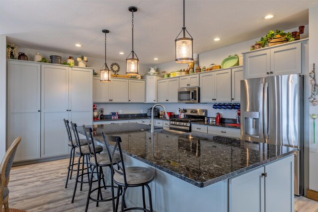 2320 Kenai Rd, Helena, MT 59602 - kitchen with appliances with stainless steel finishes, a sink, light wood-type flooring, a kitchen bar, and decorative light fixtures