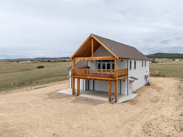 2320 Kenai Rd, Helena, MT 59602 - view of front of house with central AC unit, a deck, dirt driveway, a garage, and a view of rural / pastoral area