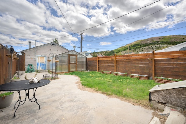 505 Oak St, Anaconda, MT 59711 - fenced backyard with an exterior structure, a patio, an outdoor structure, and a mountain view