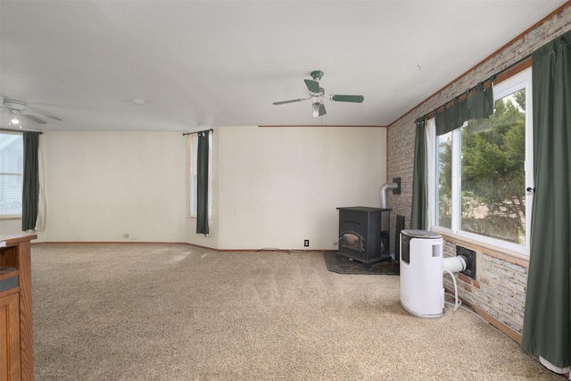505 Oak St, Anaconda, MT 59711 - unfurnished living room featuring ceiling fan, a wood stove, carpet flooring, brick wall, and baseboards
