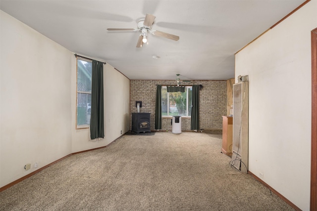 505 Oak St, Anaconda, MT 59711 - unfurnished living room featuring a wood stove, ceiling fan, carpet flooring, brick wall, and baseboards