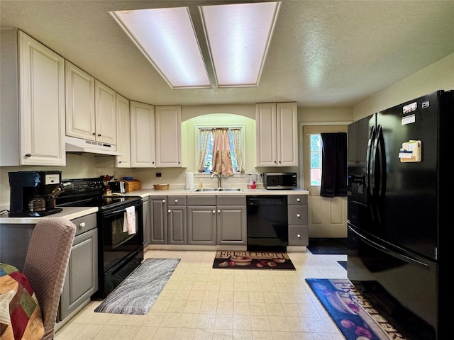172 Garden Rd, Libby, MT 59923 - kitchen featuring black appliances, a sink, under cabinet range hood, light countertops, and gray cabinetry