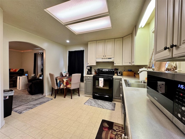 172 Garden Rd, Libby, MT 59923 - kitchen with black electric range oven, under cabinet range hood, stainless steel microwave, arched walkways, and light countertops