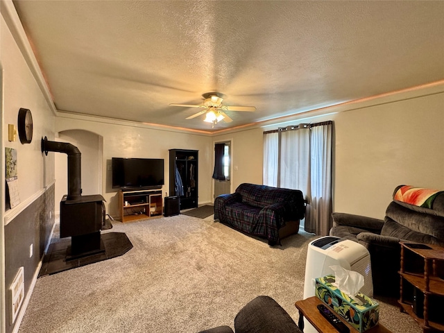 172 Garden Rd, Libby, MT 59923 - living area with carpet floors, a ceiling fan, a wood stove, ornamental molding, and a textured ceiling
