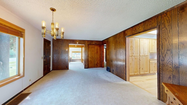 906 11th St E, Polson, MT 59860 - spare room with a chandelier, wooden walls, light colored carpet, and a textured ceiling